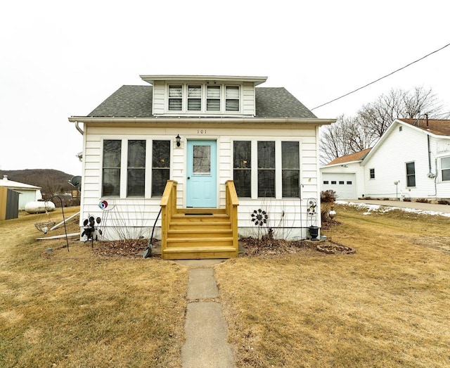 bungalow featuring a garage and a front lawn