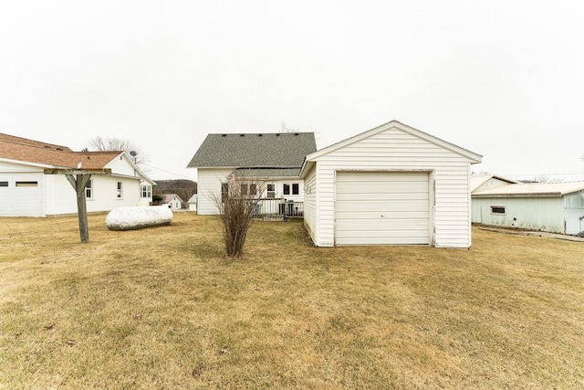 rear view of house with a garage, an outdoor structure, and a yard