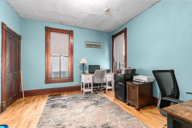 home office with light hardwood / wood-style flooring