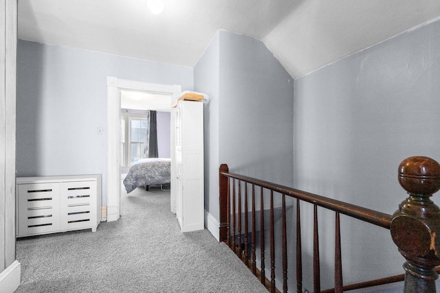 corridor with vaulted ceiling and carpet flooring