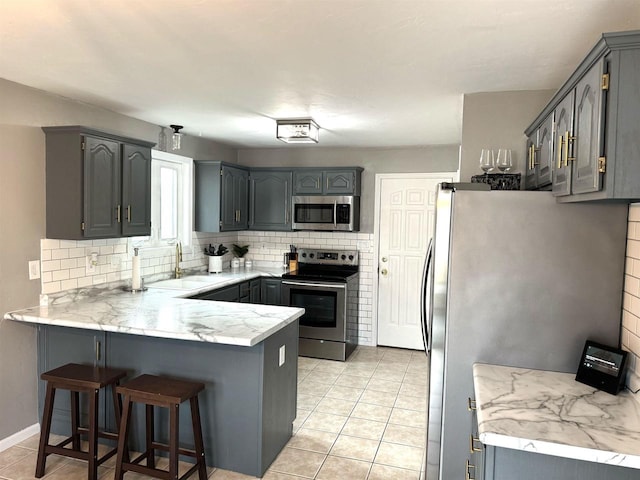 kitchen with gray cabinetry, sink, and appliances with stainless steel finishes