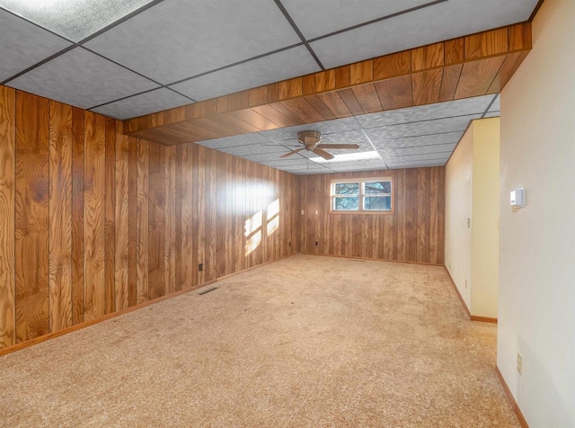 carpeted spare room featuring ceiling fan and wood walls