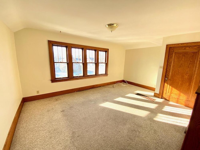 carpeted spare room featuring lofted ceiling