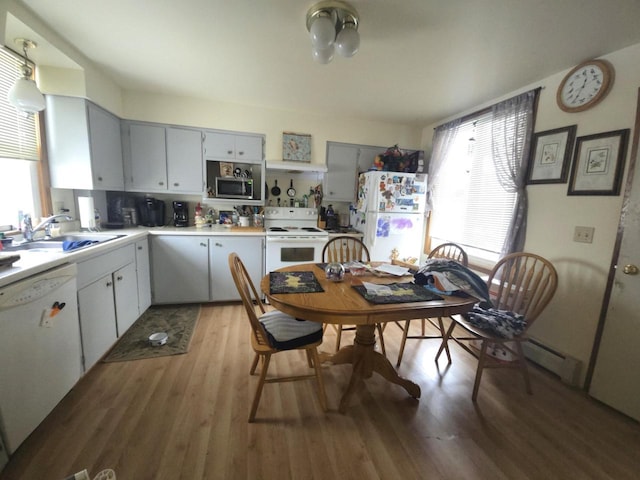 kitchen with sink, white appliances, light hardwood / wood-style flooring, and decorative light fixtures