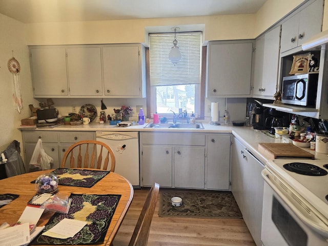 kitchen with gray cabinets, sink, white appliances, and light wood-type flooring