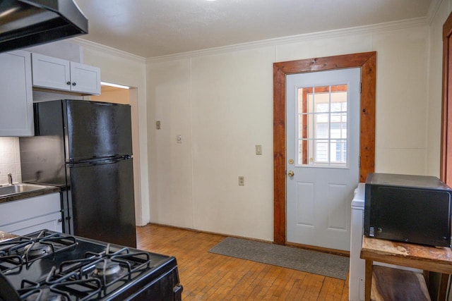 kitchen with white cabinetry, crown molding, light wood-type flooring, decorative backsplash, and black appliances