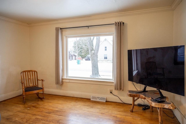 living area featuring crown molding and light hardwood / wood-style floors