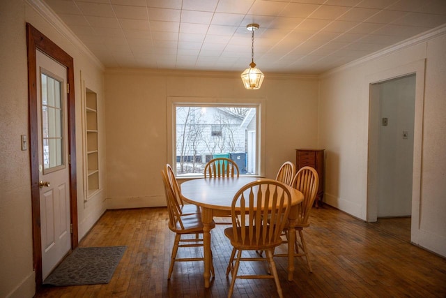 dining space with wood-type flooring, built in features, and crown molding