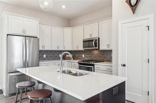 kitchen featuring stainless steel appliances, an island with sink, sink, and white cabinets