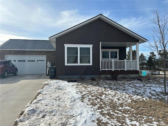 view of front of house featuring metal roof, a porch, a garage, concrete driveway, and a standing seam roof