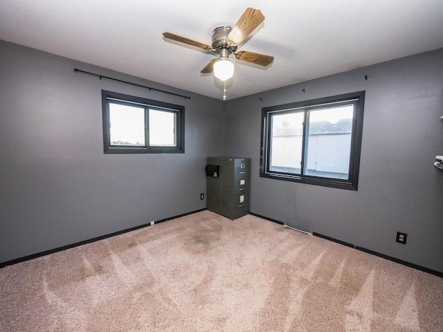 carpeted spare room featuring plenty of natural light and ceiling fan