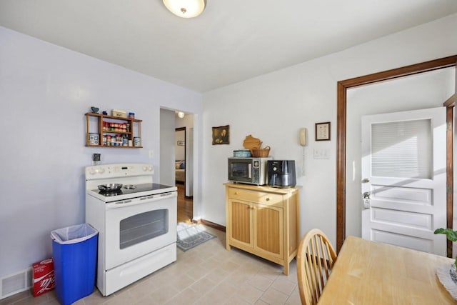 kitchen featuring light brown cabinetry, light tile patterned floors, and white electric stove