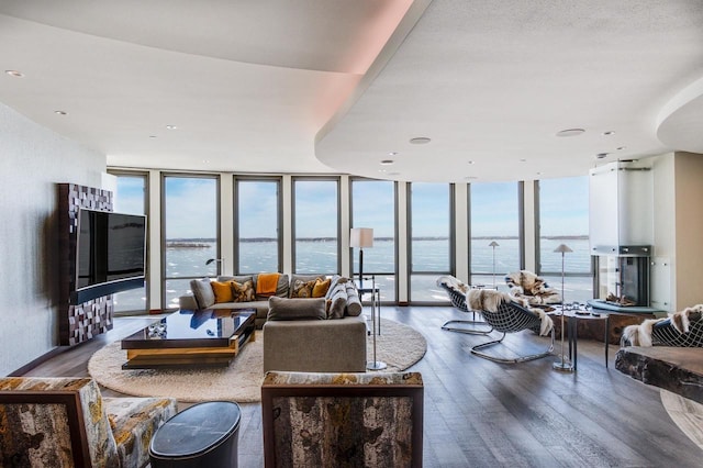 living room with hardwood / wood-style floors, a wealth of natural light, a wall of windows, and a water view