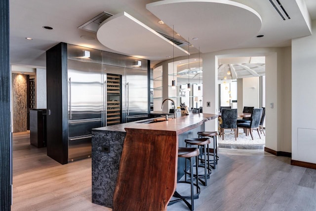 bar with sink, light hardwood / wood-style flooring, and high quality fridge