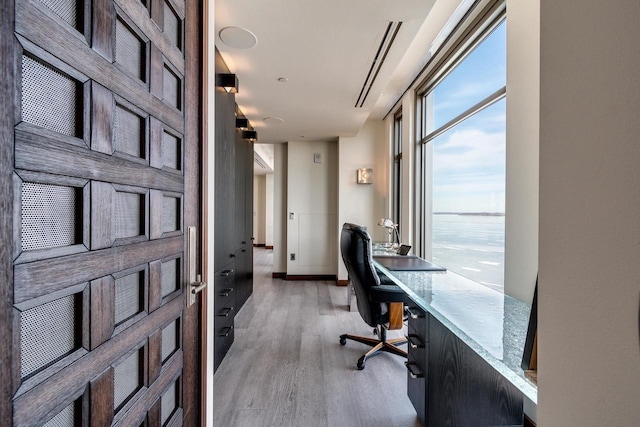 office featuring light hardwood / wood-style floors and a water view