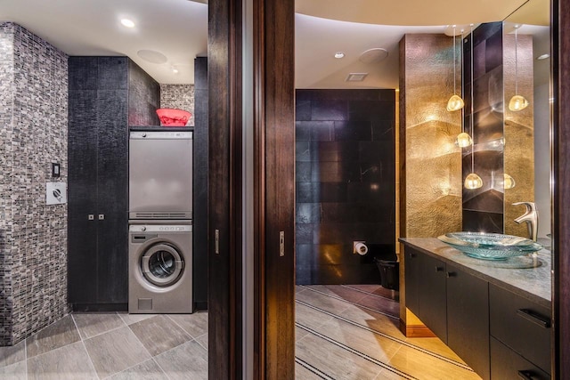 interior space featuring tile walls, sink, and stacked washing maching and dryer