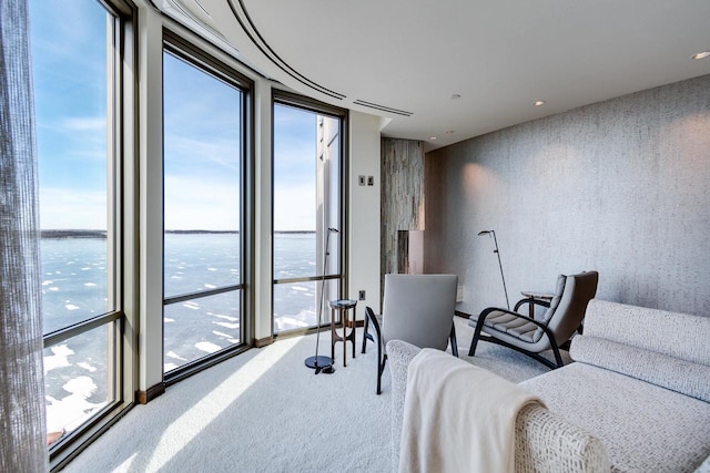 living area with carpet flooring, expansive windows, and a water view