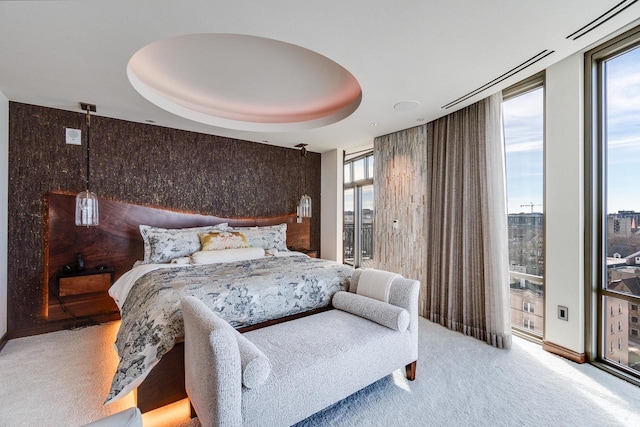 bedroom featuring carpet floors, floor to ceiling windows, and a raised ceiling