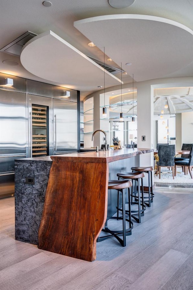 bar featuring hardwood / wood-style floors, sink, and hanging light fixtures