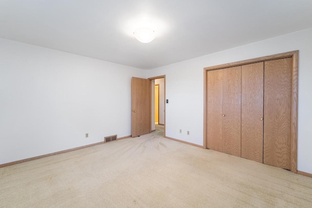 unfurnished bedroom featuring light colored carpet and a closet