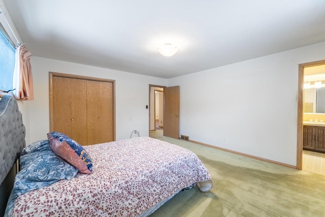 bedroom with ensuite bathroom, carpet flooring, and a closet