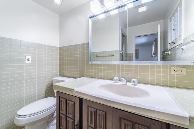 bathroom with vanity, tile walls, and toilet