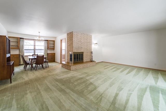 unfurnished living room featuring a brick fireplace, a chandelier, and carpet flooring