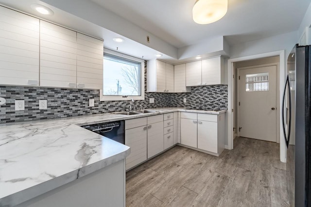 kitchen featuring sink, refrigerator, backsplash, black dishwasher, and light hardwood / wood-style floors