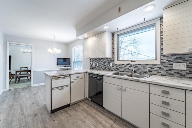 kitchen featuring sink, hanging light fixtures, light wood-type flooring, kitchen peninsula, and dishwasher