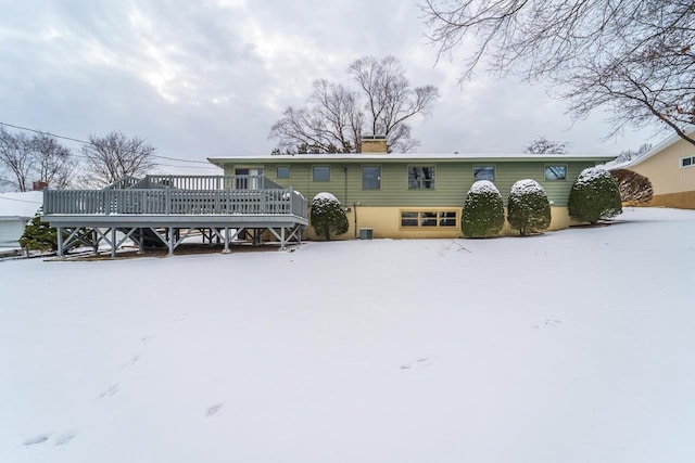 snow covered house featuring a wooden deck