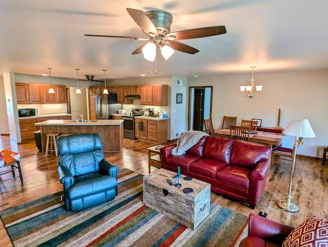 living room featuring sink, ceiling fan with notable chandelier, and light hardwood / wood-style floors