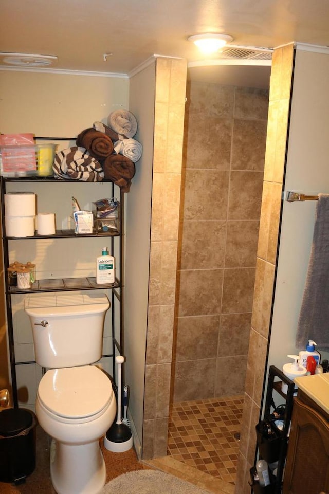 bathroom with ornamental molding, vanity, toilet, and a tile shower