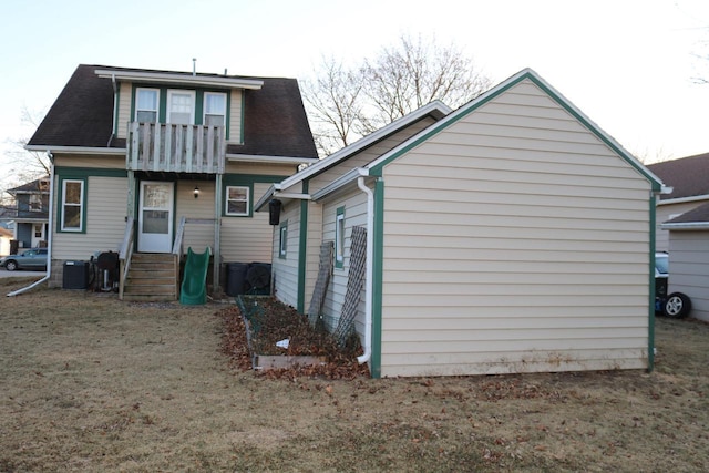 back of house with a lawn and a balcony