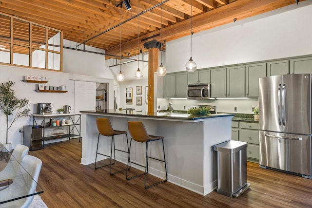 kitchen with hanging light fixtures, green cabinets, a towering ceiling, and appliances with stainless steel finishes