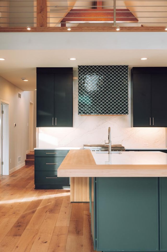 kitchen with sink, a center island with sink, light hardwood / wood-style flooring, and a kitchen bar