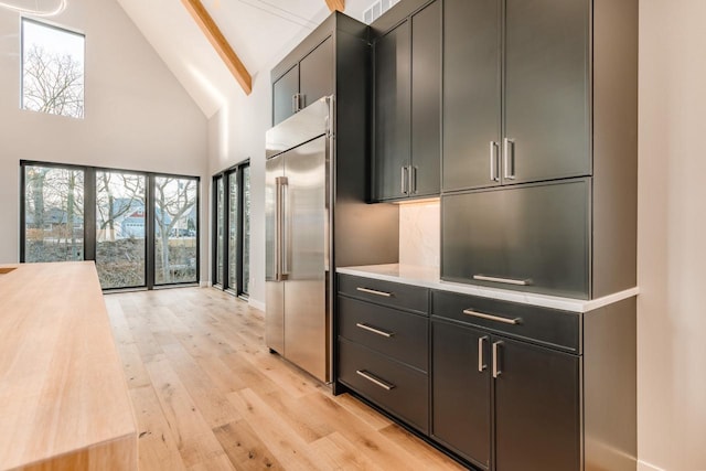 kitchen with butcher block countertops, high vaulted ceiling, built in refrigerator, beam ceiling, and light wood-type flooring