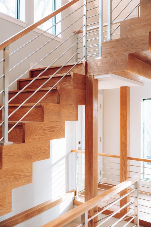 stairs featuring plenty of natural light, wooden walls, and a high ceiling