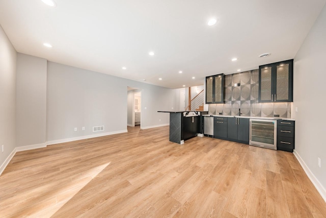 kitchen with wine cooler, light hardwood / wood-style floors, a kitchen bar, stainless steel dishwasher, and kitchen peninsula