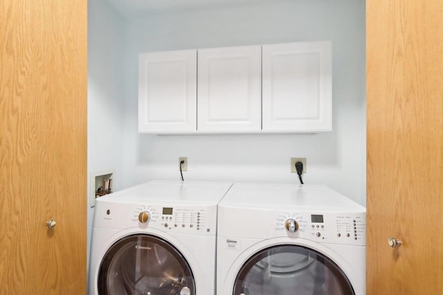 clothes washing area with cabinets and washing machine and dryer