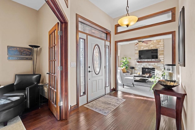 entryway featuring a stone fireplace and dark wood-type flooring