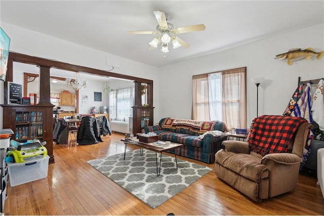 living room featuring ceiling fan with notable chandelier and light hardwood / wood-style flooring