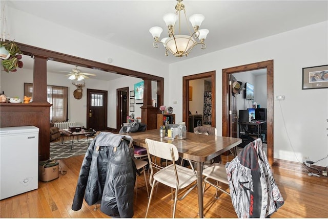 dining space with ceiling fan with notable chandelier and light hardwood / wood-style floors