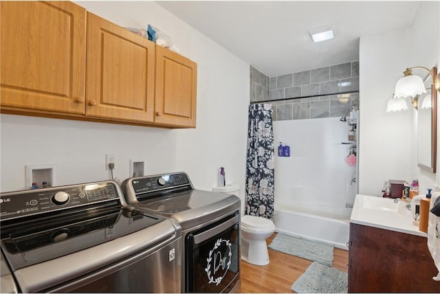 clothes washing area with sink, hardwood / wood-style flooring, and washer and clothes dryer