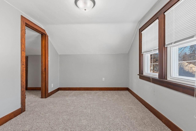 additional living space with vaulted ceiling and light carpet