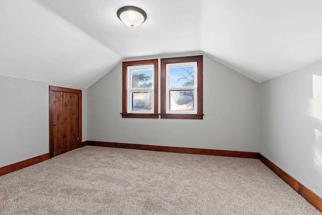 bonus room with vaulted ceiling and carpet floors