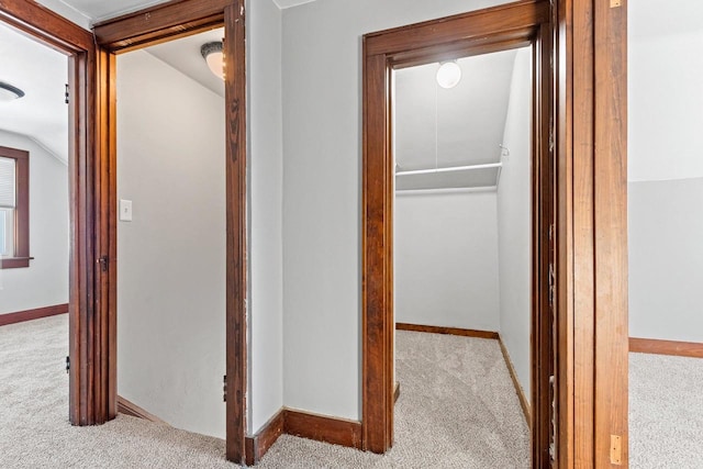 hall with lofted ceiling and light carpet