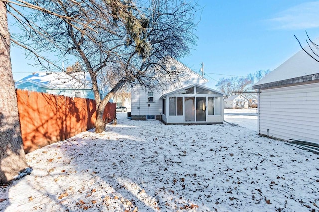 snow covered back of property with a sunroom