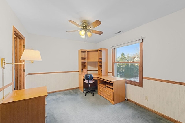 office space with light carpet, wooden walls, and ceiling fan