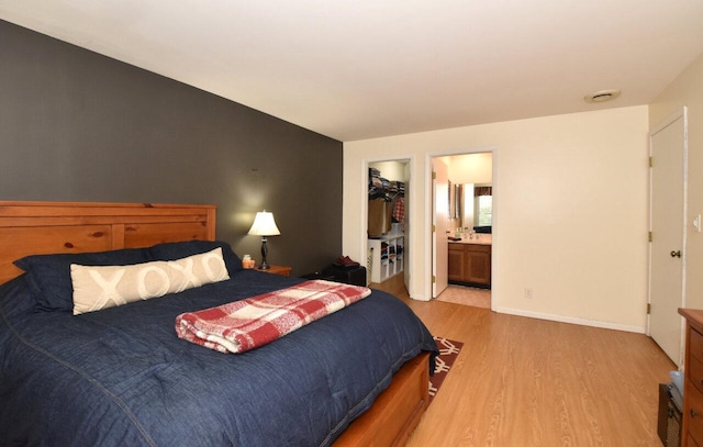 bedroom with ensuite bath, light hardwood / wood-style floors, a closet, and a walk in closet