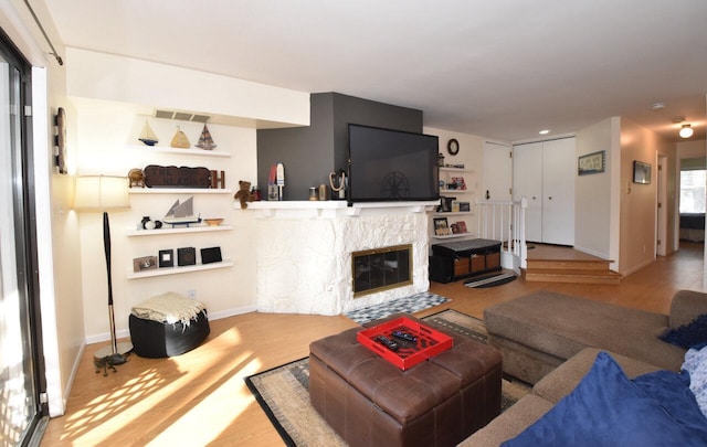 living room featuring a stone fireplace and wood-type flooring